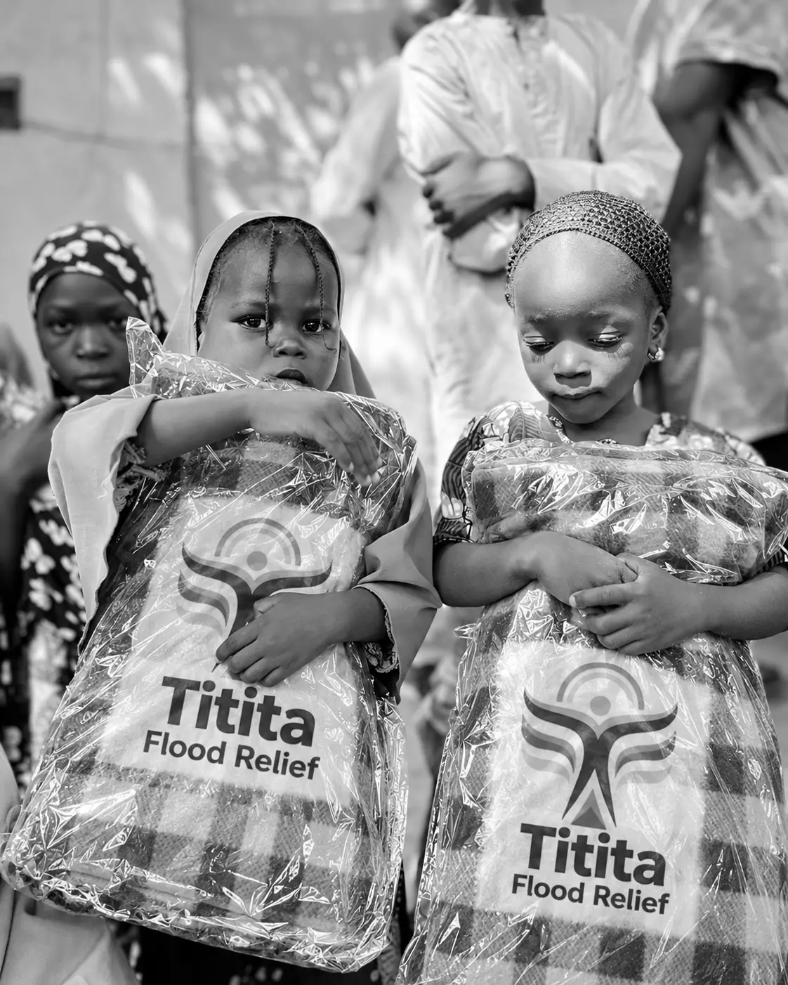 Two girls holding Titita Flood Relief blanket packs