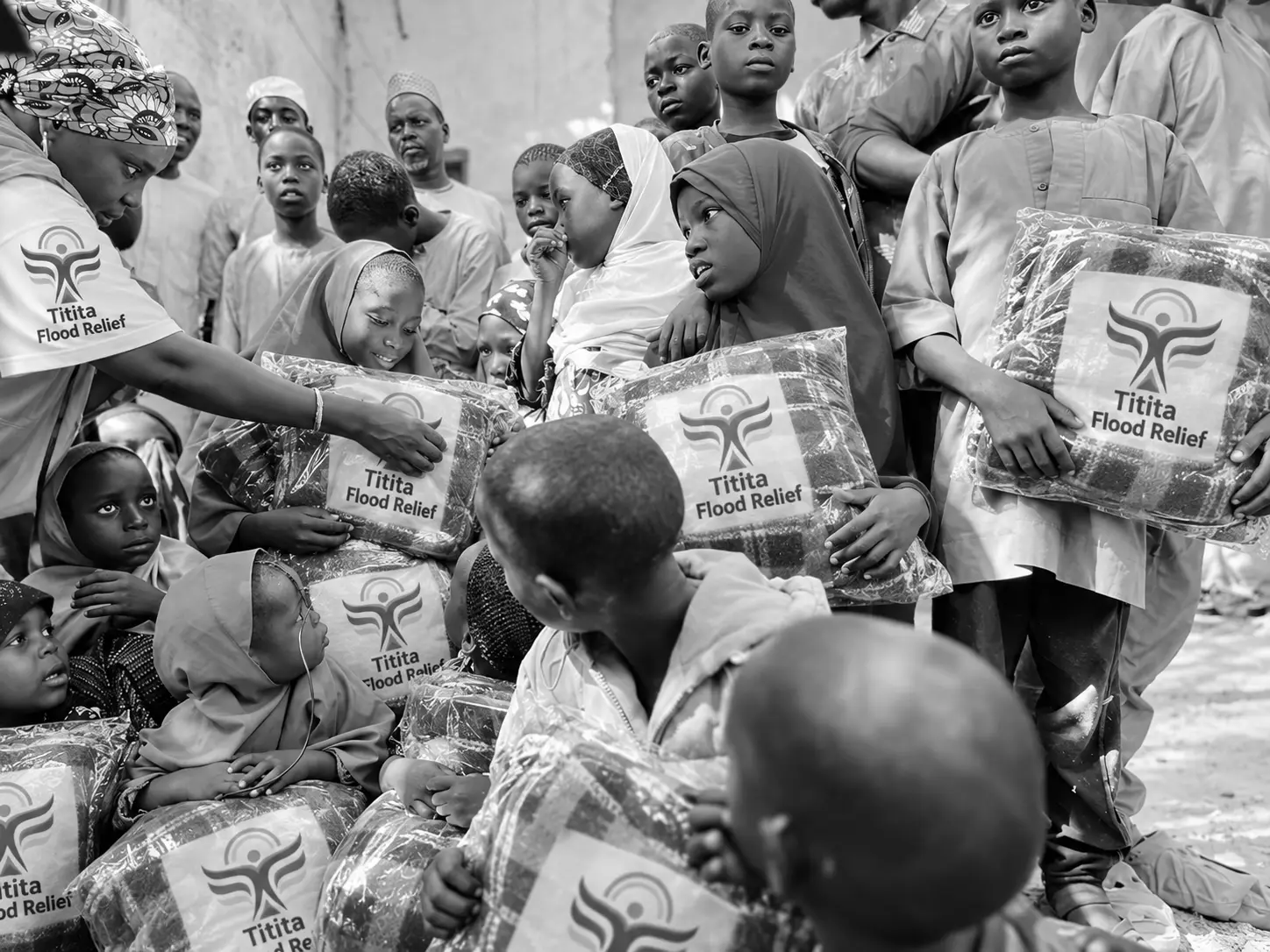 A Titita volunteer handing blanket packs to children