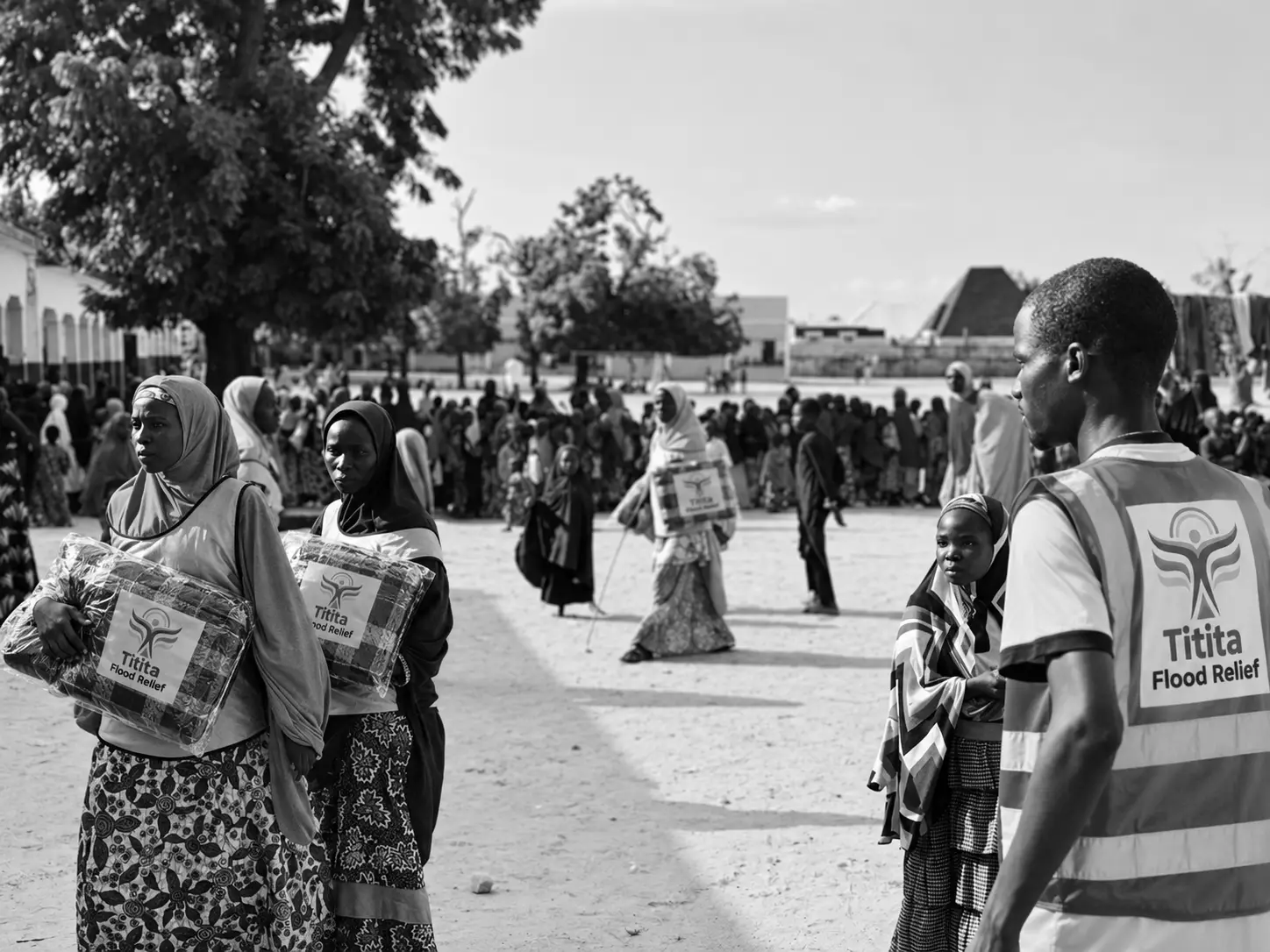 Women carrying Titita Flood Relief blanket packs across a distribution ground